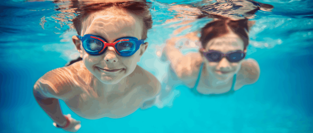Two children with goggles swimming underwater in a pool