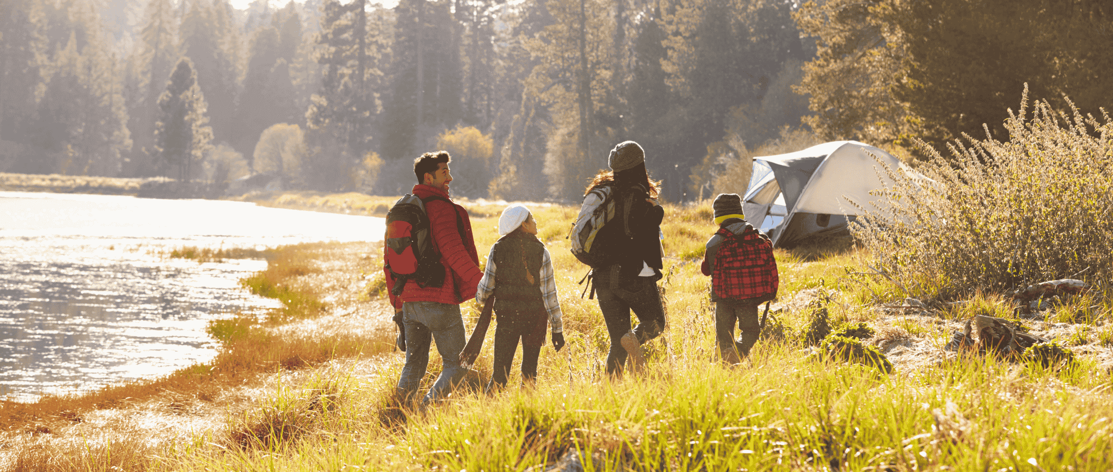 Happy family of four camping together in the wilderness
